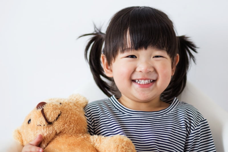 Kids Dentist Singapore - a child smiling happy with her primary teeth after visiting the dentist's office