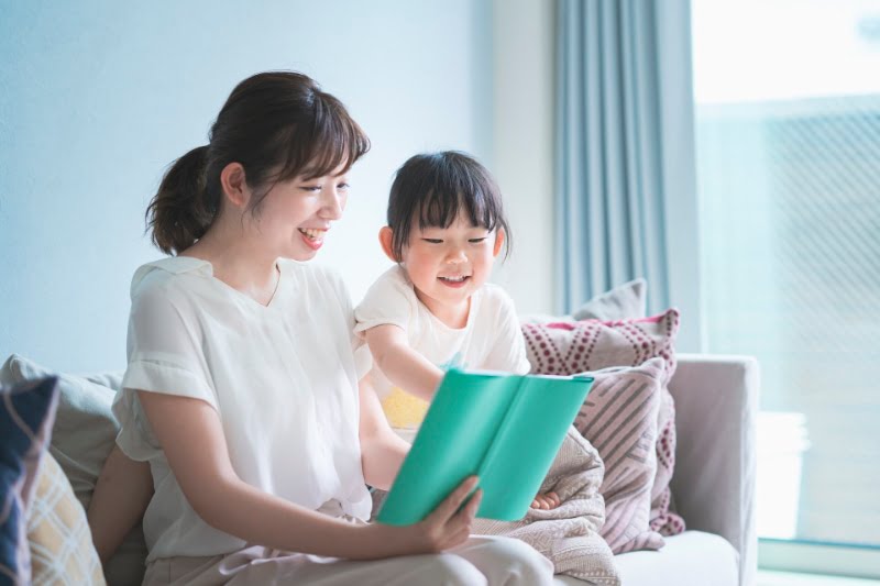 Mother and daughter sitting on the sofa and reading a picture book